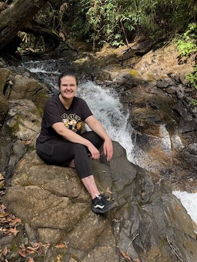 Calleigh sitting on rock next to a waterfall in Baja Verapaz, Guatemala. 